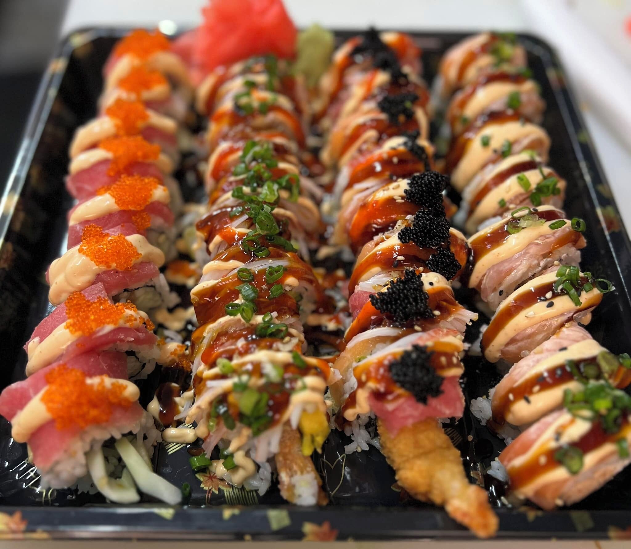 A tray of sushi rolls with various toppings and garnishes.