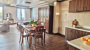A spacious dining area with a wooden table and chairs, a kitchen with dark wooden cabinets, and a large window providing natural light. - Seaview Garden Hotel & Residences (Basseterre)
