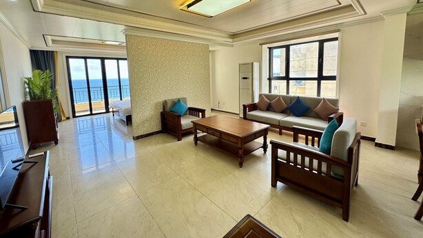 A spacious living room with a sofa, armchairs, and a coffee table. There is a large window providing a view of the sea. - Seaview Garden Hotel & Residences (Basseterre)