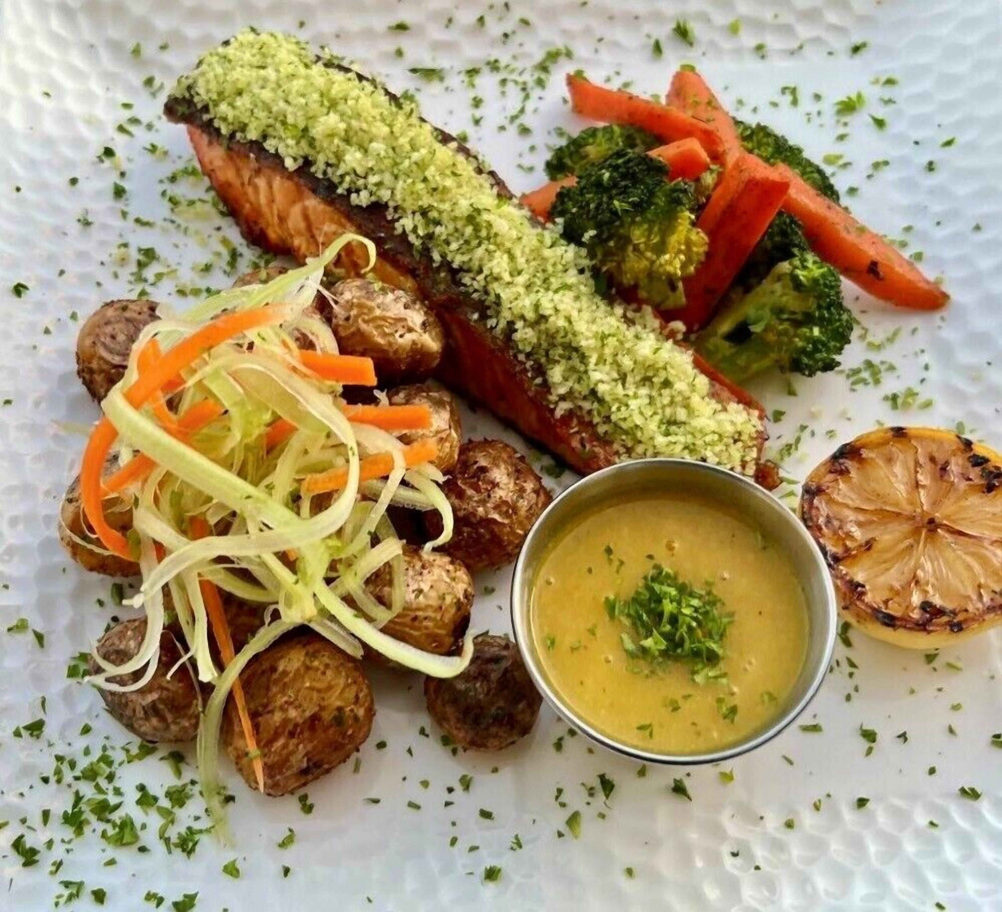 A plate with salmon, roasted vegetables, and a bowl of soup.