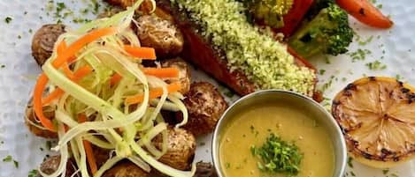 A plate with salmon, roasted vegetables, and a bowl of soup.
