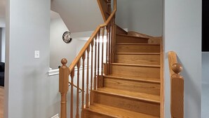A wooden staircase with a white wall and a clock. - Comfy home sleeps 13+ guest with wifi &parking Netflix (Brampton)