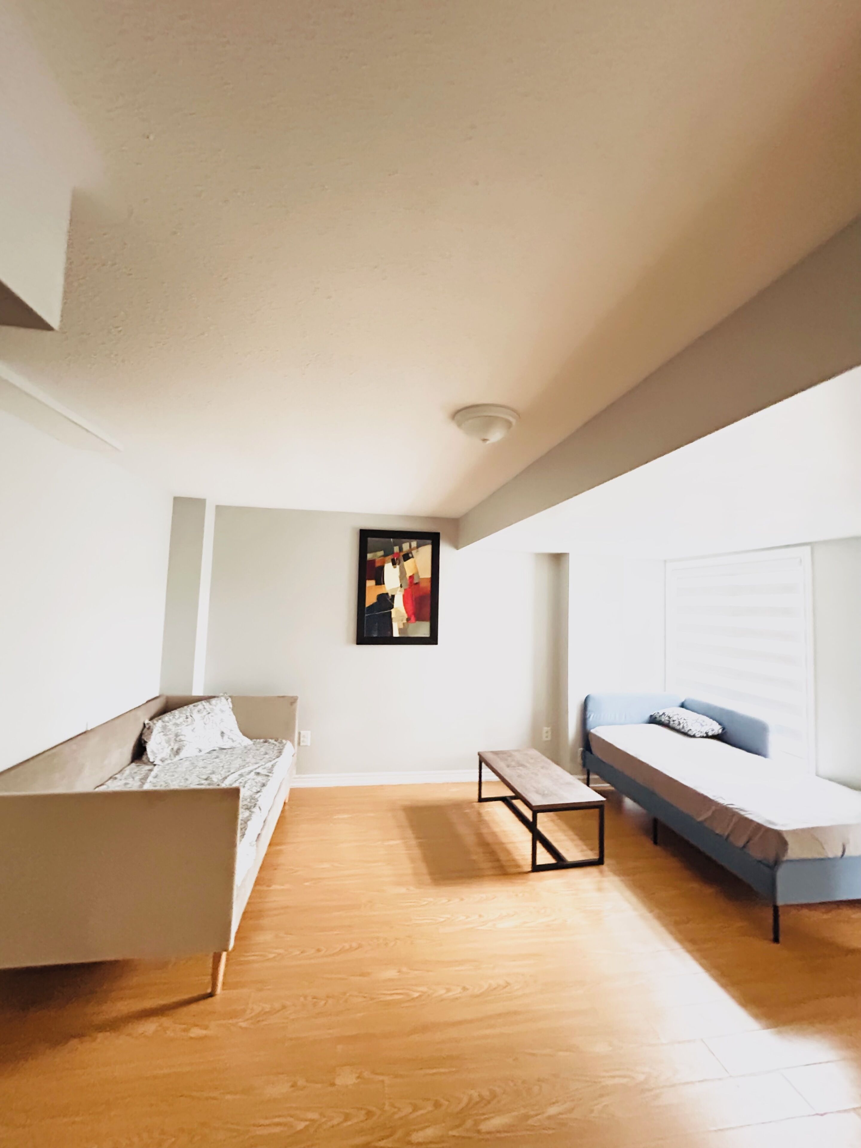 Une pièce moderne et minimaliste, avec un plancher en bois, un canapé, un banc et un lit.