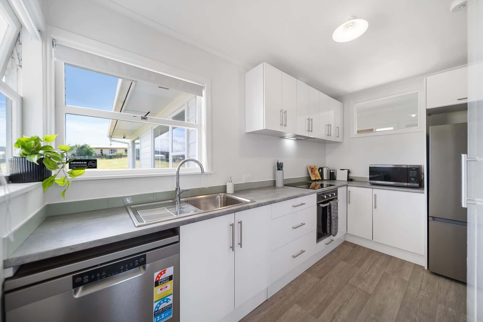 A modern kitchen with white cabinets, stainless steel appliances, and a dishwasher with an energy rating sticker.