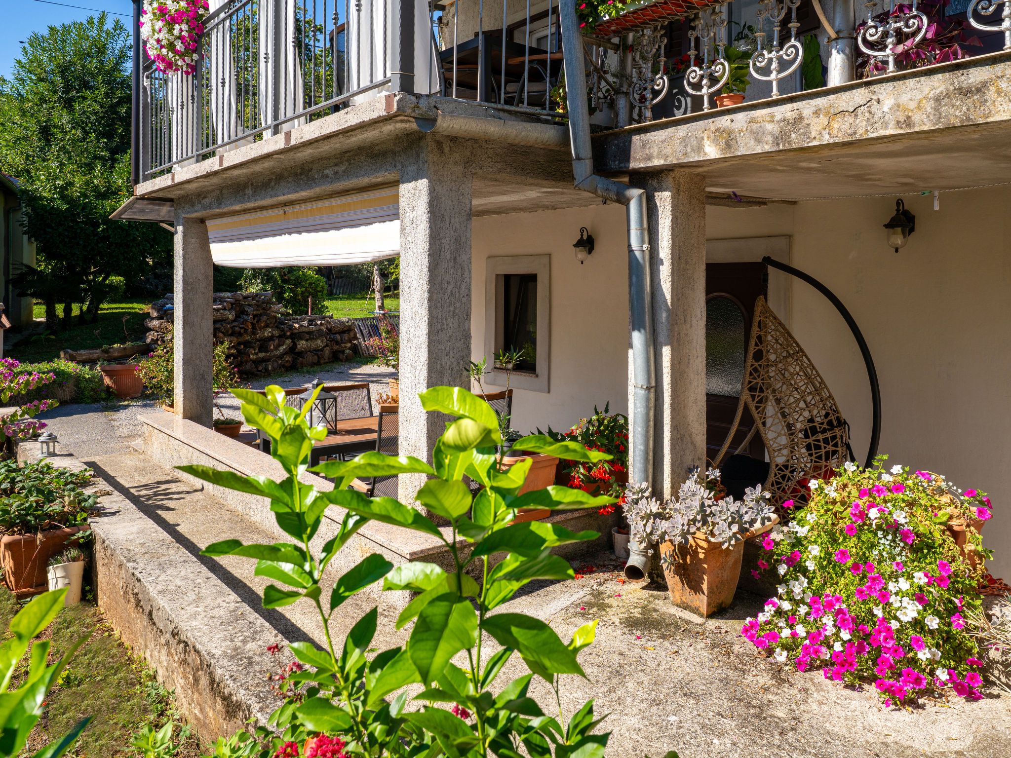 Une cour avec un banc en pierre, des plantes en pot et un balcon doté de rampes en métal.