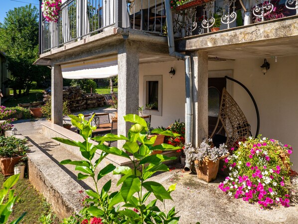 Une cour avec un banc en pierre, des plantes en pot et un balcon doté de rampes en métal.