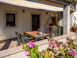 An outdoor patio with a table and chairs, a hanging chair, and a door. - Apartment Mrak by Interhome (Lovran)