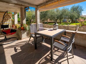 Eine Terrasse im Freien mit Tisch, Stühlen, einer Hängematte und Topfpflanzen.