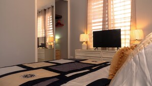A hotel room with a bed, a television, and two lamps. - Relax in this peaceful, unique getaway paradise next to the beach in Aguada. (Aguada)