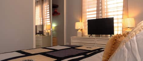 Quarto de hotel com uma cama, uma televisão e duas luminárias.