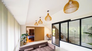 Una sala de estar moderna con un sofá, un comedor y un amplio ventanal corredero que da a un balcón.