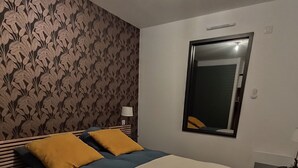 Un dormitorio con cama, espejo y un papel tapiz estampado.