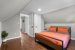 Ein Schlafzimmer mit einem Bett, einer Zimmerpflanze, einer Tür und einem Flur.