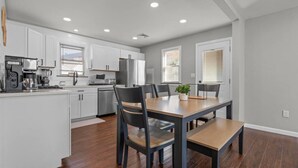 A modern kitchen with white cabinets, a dining table, and chairs. - #22- 4 Br 2 Ba house-Central CT (New Britain)