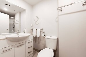 A modern bathroom with a large sink, toilet, and a shower area. - Great Little Nest in the Heart of CBD with Parking (Auckland Central)