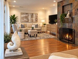 A modern living room with a fireplace, a large painting, and a comfortable seating area.