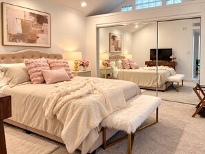 A bedroom with a large bed, a bench, a TV, and a mirror. - The Guest House - Newly Remodeled (Lynnwood)