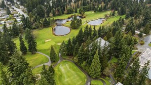 Oversigtsbillede af en golfbane med flere søer, omgivet af tæt skov og boligområder.