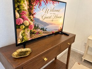 A television on a wooden console with a 'Welcome to the Guest House' message and a scenic view. - The Guest House - Newly Remodeled (Lynnwood)
