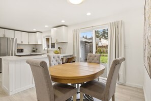 A modern kitchen with white cabinets, a central island, and a dining area with a round table and four chairs.