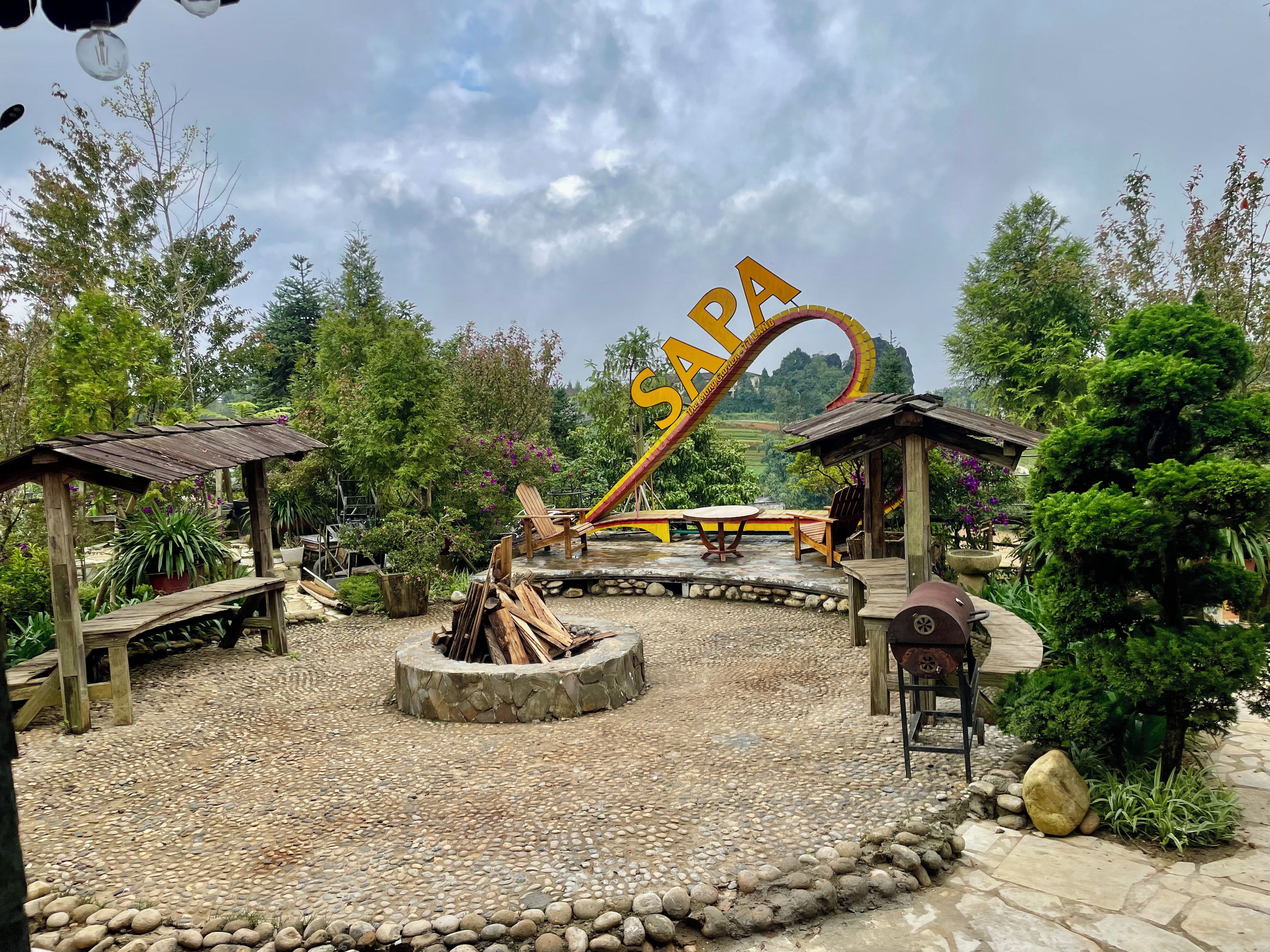 Un espace jardin aménagé avec un foyer, des bancs en bois et un grand panneau indiquant « SPA ».