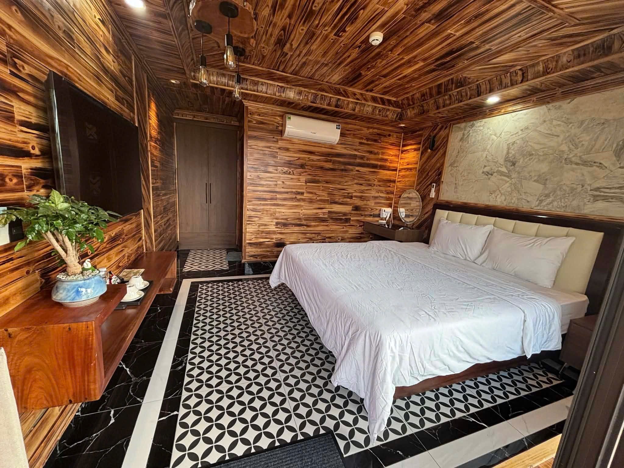 Una habitación con una cama, techo de madera, aire acondicionado de pared y piso con patrón geométrico.