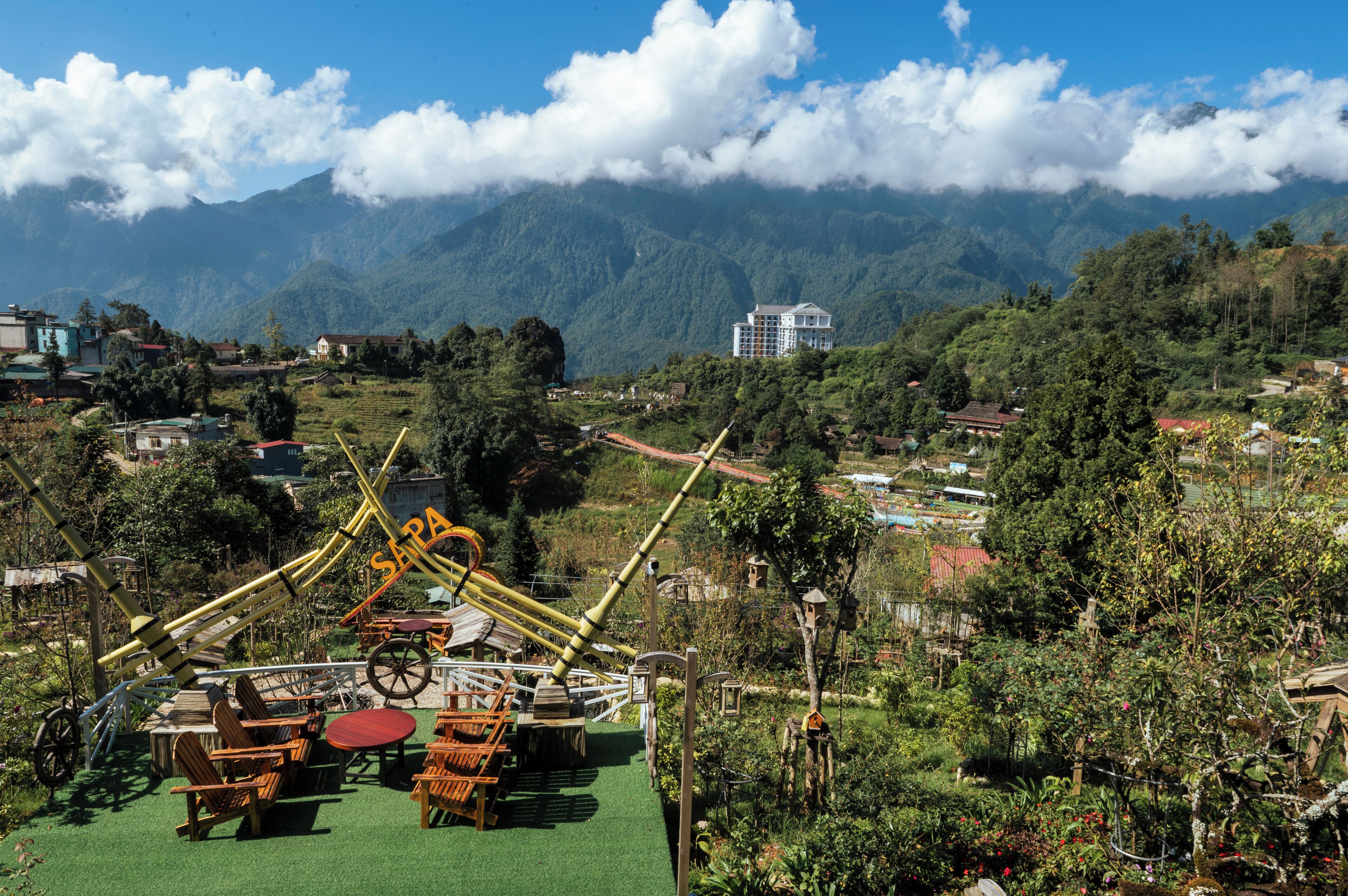 A park with a swing set, picnic tables, and a view of mountains.