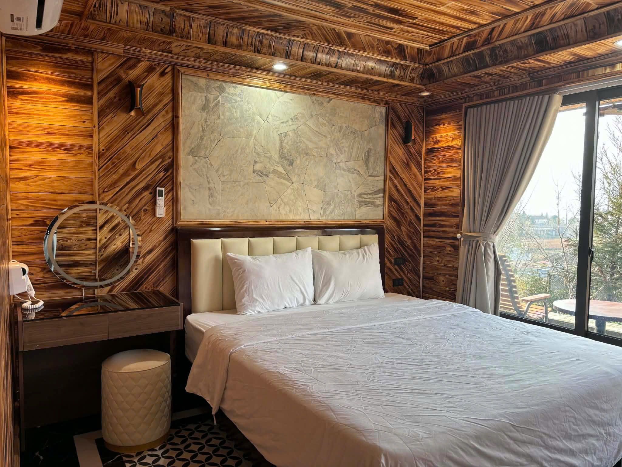 A hotel room with a bed, a bedside table with a telephone, a mirror, and a large abstract painting on the wall.