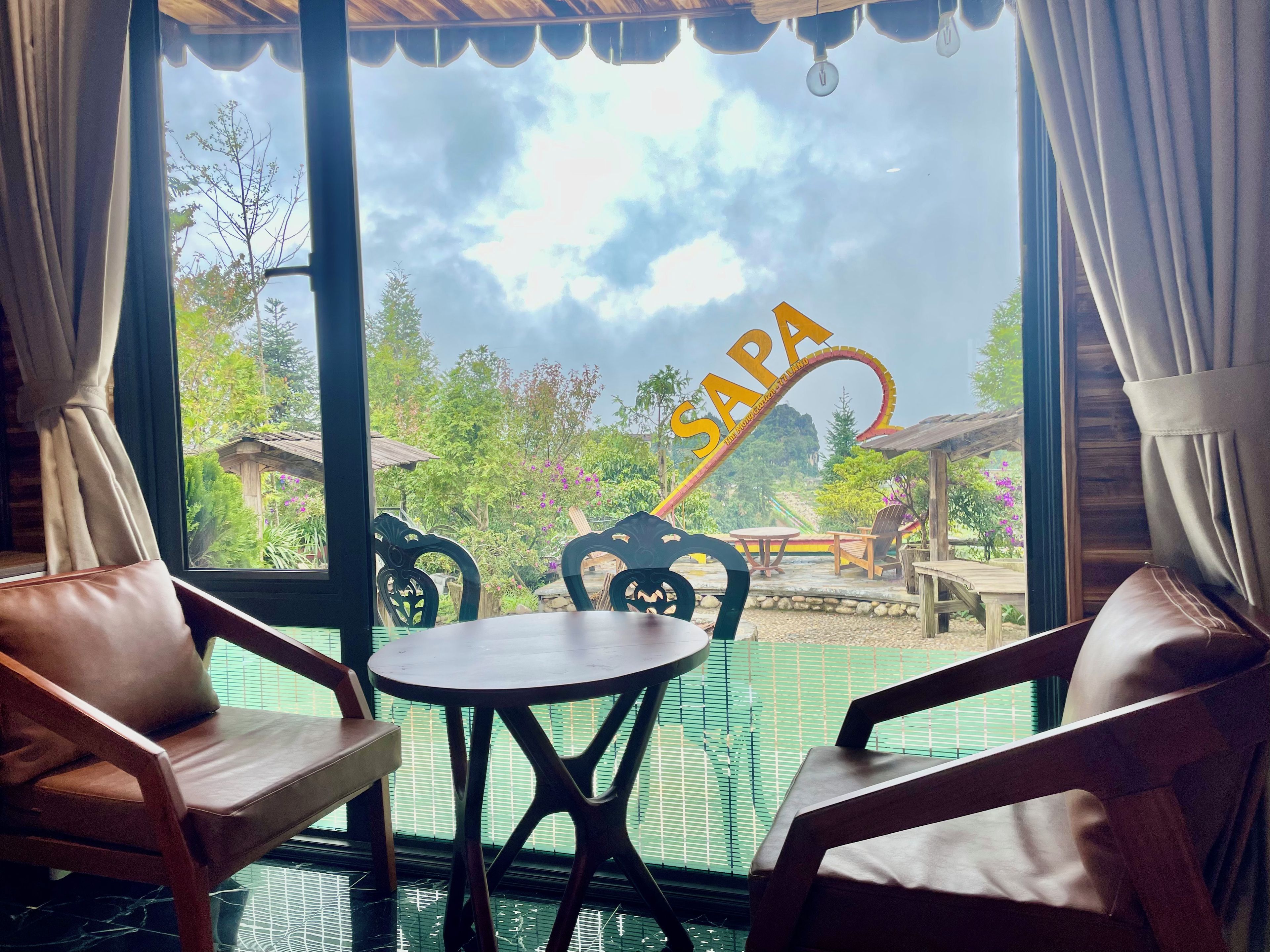 Una habitación con vista a un jardín, una mesa y dos sillas.