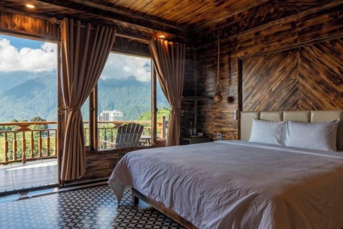 Ein Schlafzimmer mit einem großen Bett, Holzwänden, Bergblick und einem Balkon.