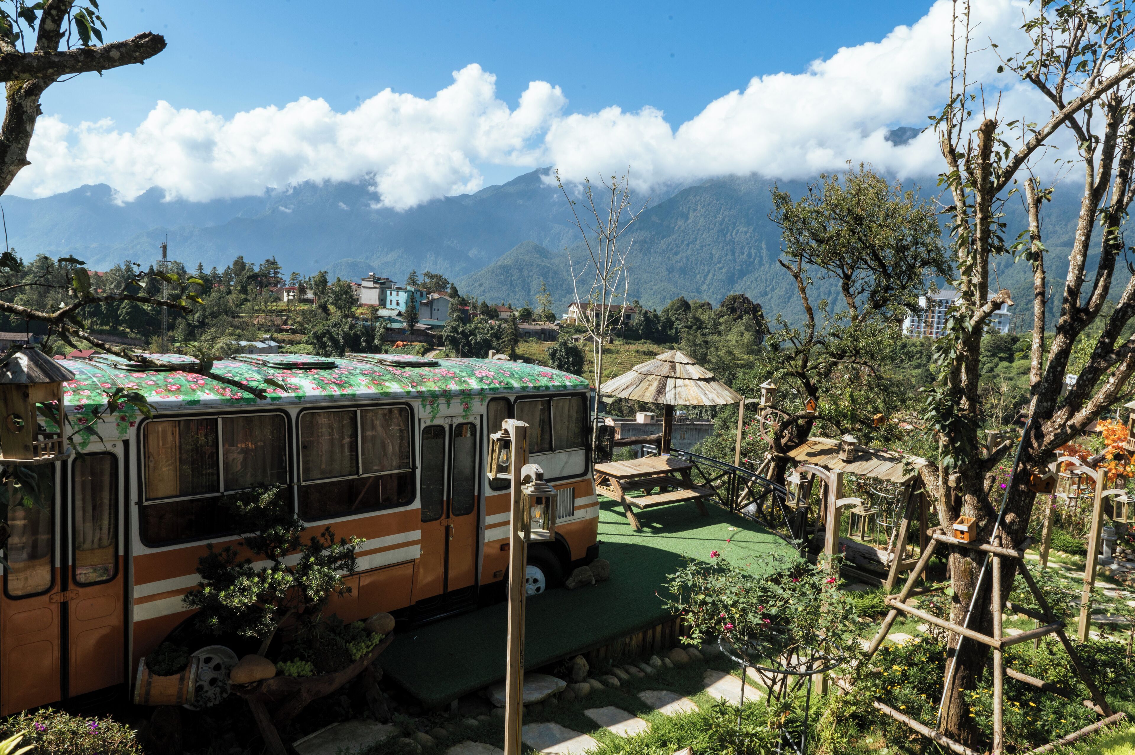 Un autobús estacionado en un jardín con una montaña al fondo.