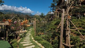 Un sendero en un jardín con estructuras de madera y vistas a montañas al fondo.