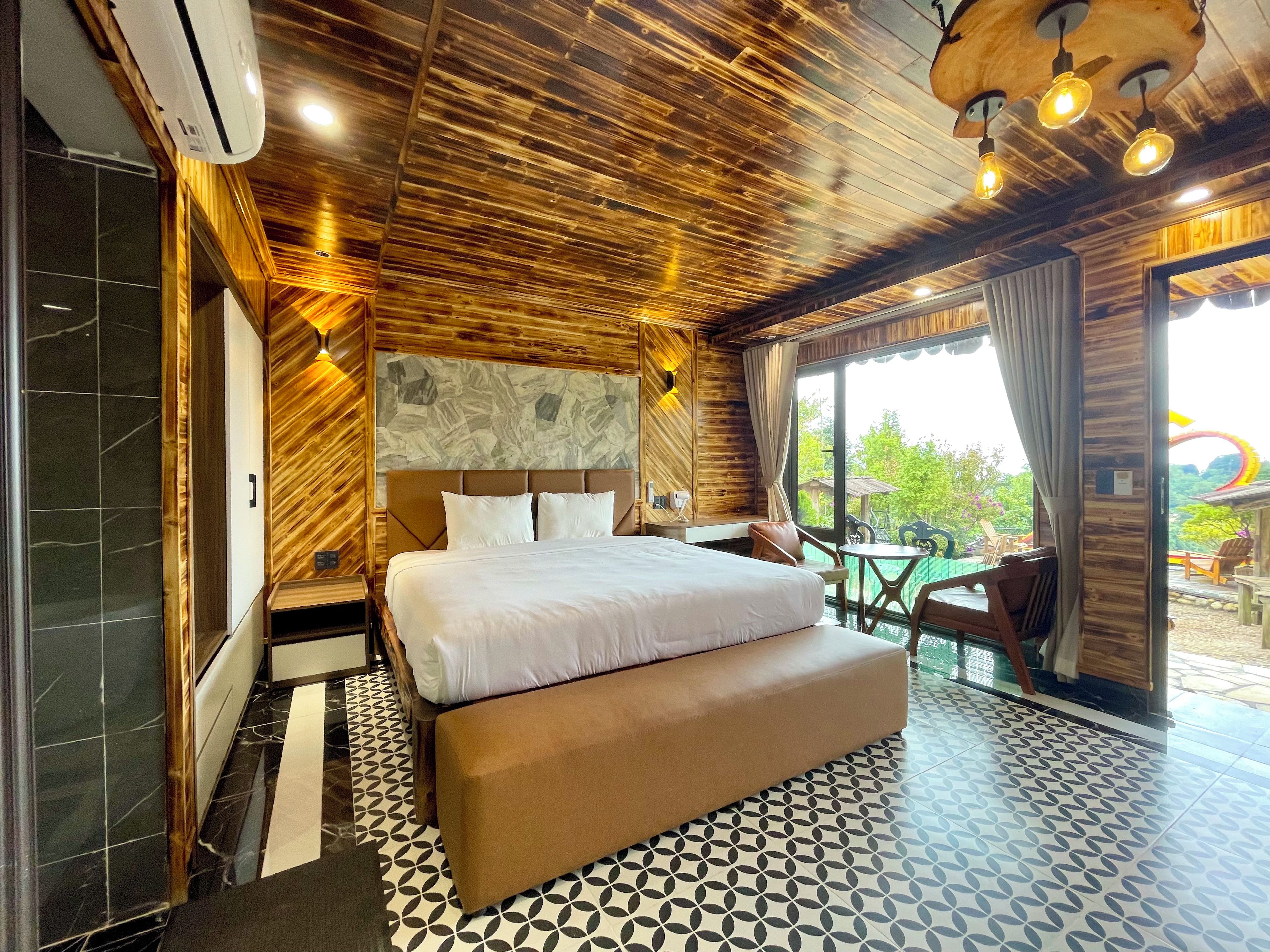 A modern hotel room with a large bed, a wooden ceiling, and a view of the outdoors.