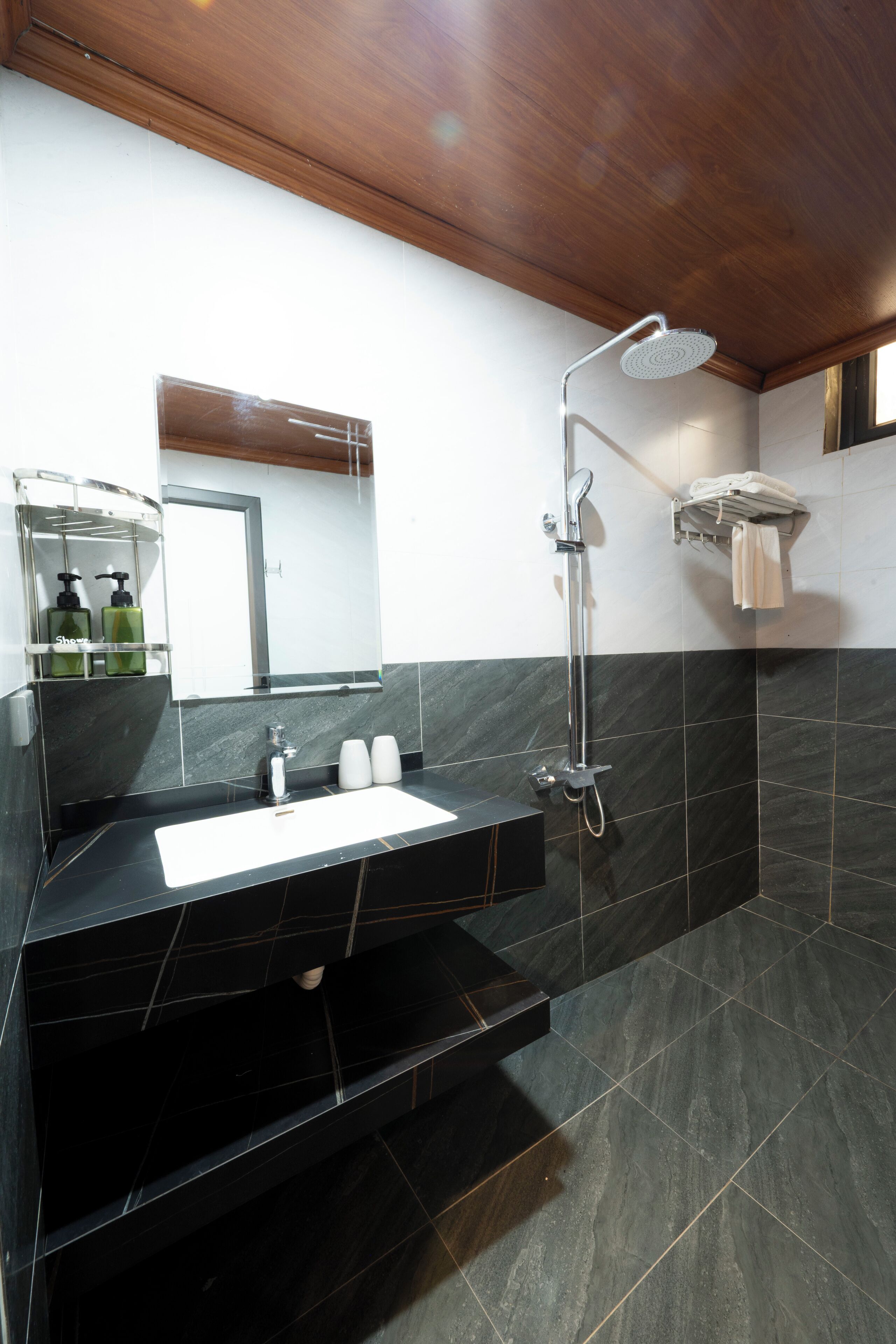 Ein modernes Badezimmer mit einem schwarzen Marmorwaschbecken, einer Duschkabine aus Glas und einer Holzbodenverkleidung.