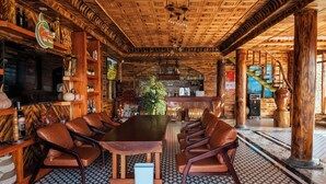 Un interior de madera con una gran mesa y sillas de cuero, rodeado de estanterías con diversos objetos.