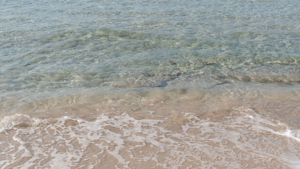 Una playa con aguas cristalinas y una orilla arenosa.