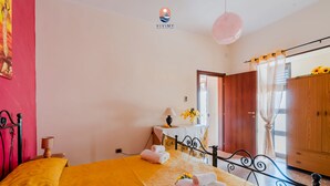 Habitación de hotel con cama, armario de madera, escritorio con lámpara y vistas al exterior.
