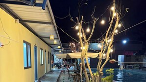 Un cortile con piscina, posti a sedere all'aperto e luci decorative.