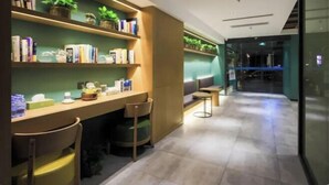 Ein modernes Interieur mit einer Rezeption, einer Sitzecke und Regalen mit Büchern und Pflanzen.