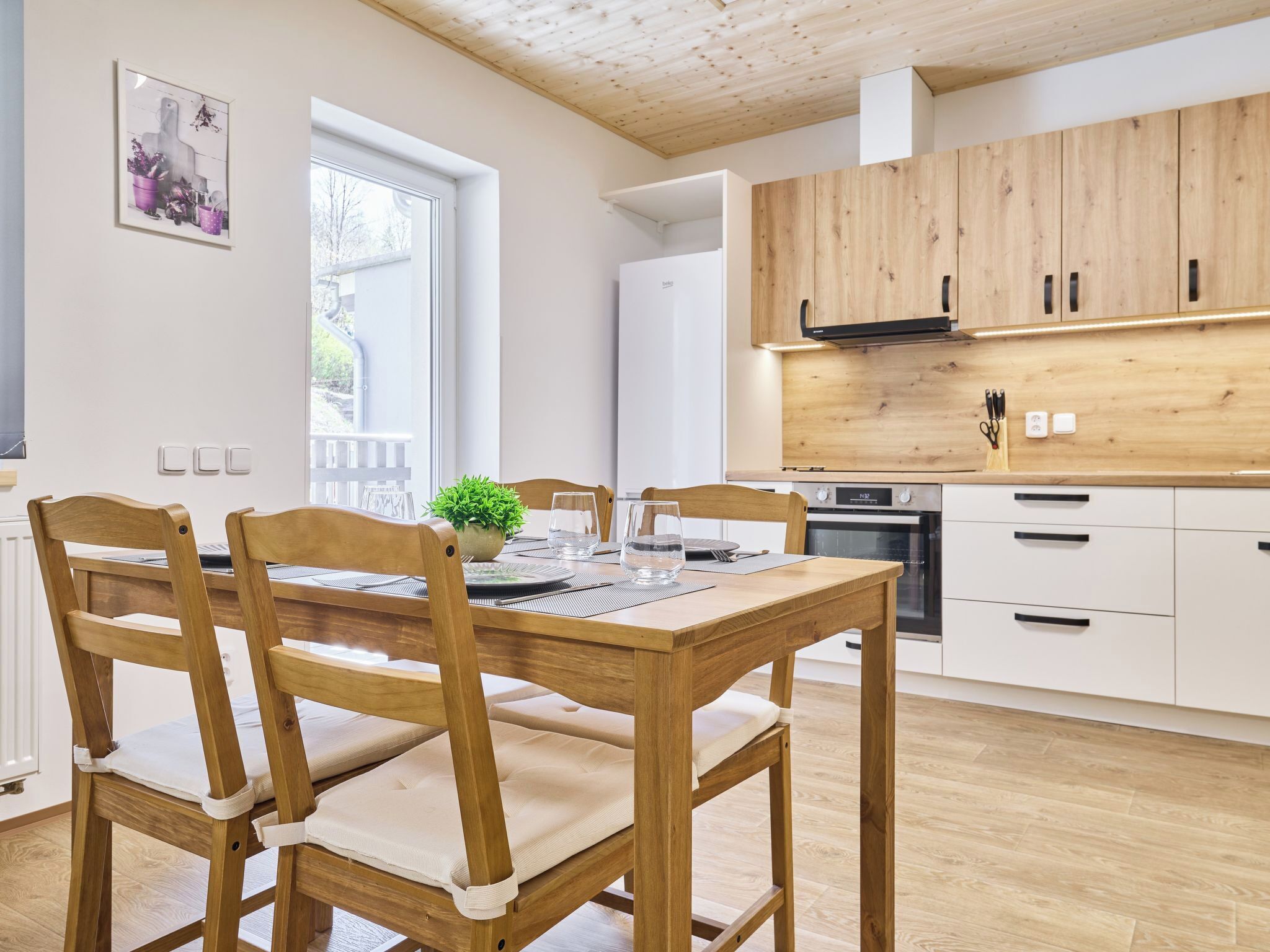 Una cocina moderna con armarios de madera, una mesa de comedor con sillas y una ventana con vistas.