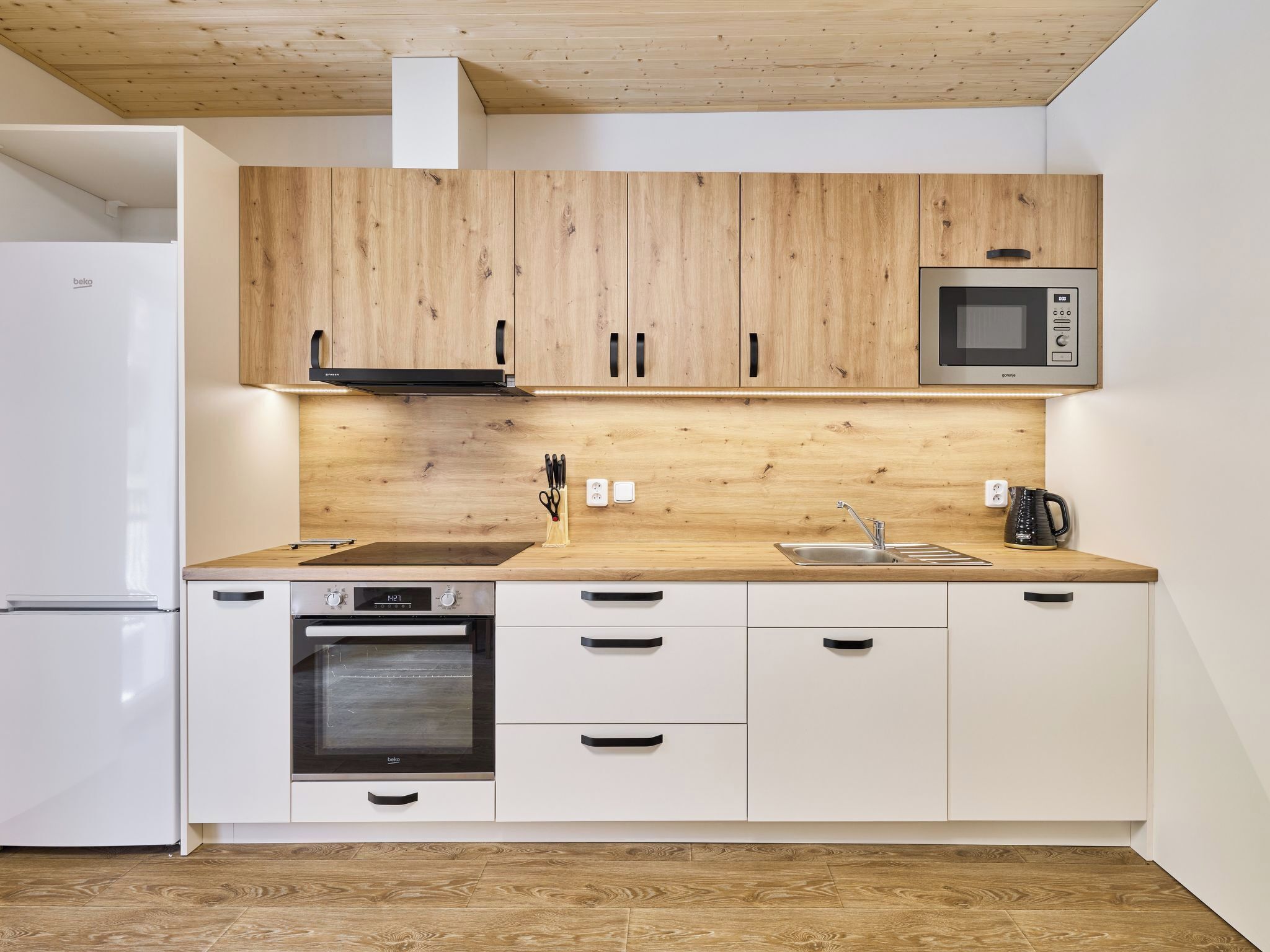 Une cuisine moderne avec des meubles en bois, un four à micro-ondes encastré, une cuisinière et un évier.