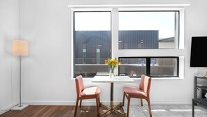 Et moderne værelse med et stort vindue, to stole, et bord med en vase og en gulvlampe.