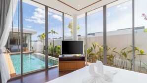 Une chambre d’hôtel moderne dotée d’une grande fenêtre, d’une piscine et d’un téléviseur à écran plat.