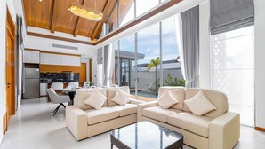Un salon moderne avec un canapé d’angle, une table basse en verre et un coin repas comprenant une table et des chaises.