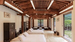A spacious room with a wooden ceiling, a large window, and a sofa. - Rakkojae Hahoe Hanok Hotel  (Andong)