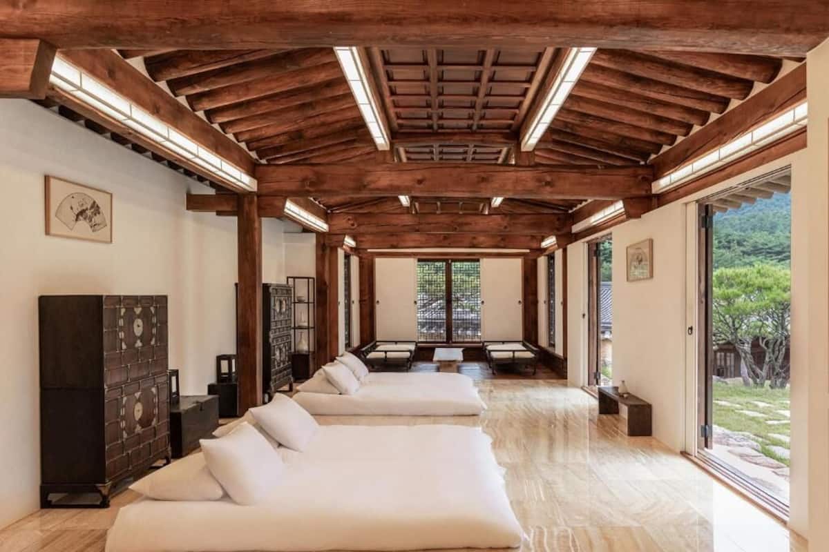A spacious room with a wooden ceiling, a large window, and a sofa.