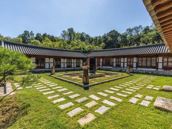 Une cour intérieure coréenne traditionnelle, avec des toits couverts de tuiles, des allées pavées de pierres et des bâtiments en bois.
