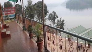 Uma varanda com vista para um rio, plantas em vasos e uma placa em língua estrangeira.