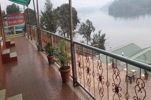 Un balcón con vistas a un río, plantas en macetas y un letrero en idioma extranjero.