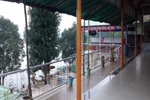 Un espacio al aire libre cubierto con barandilla metálica, plantas en macetas y una escalera que sube a un nivel superior.